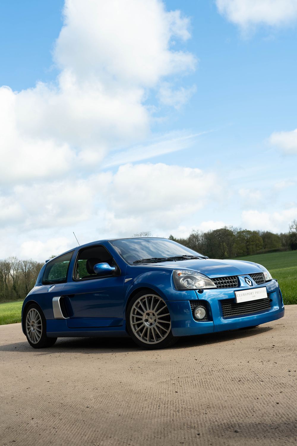 Low angle on a blue Renault Clio V6 under a big sky