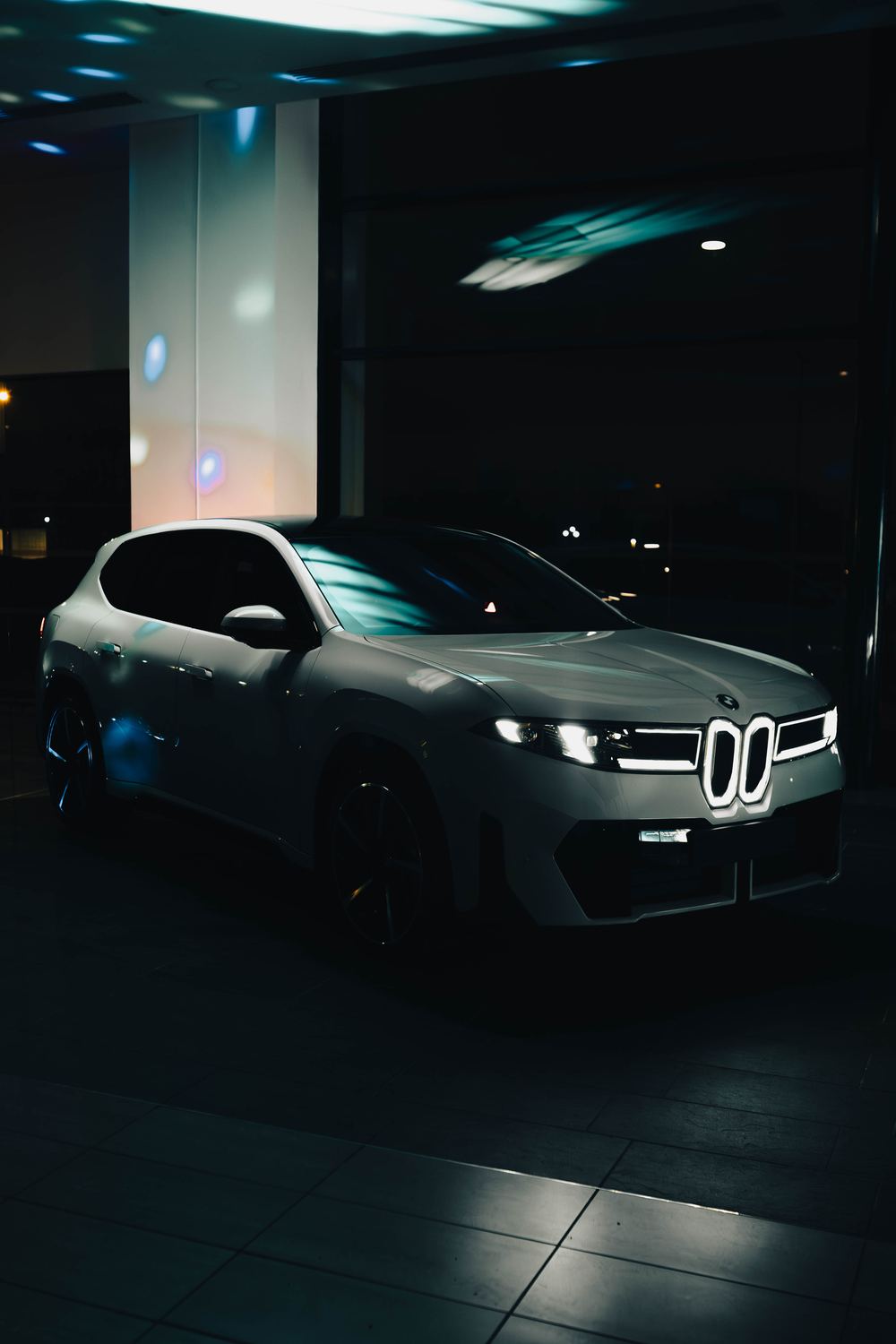 The new BMW iX3 in a darkened showroom with its grille lit
