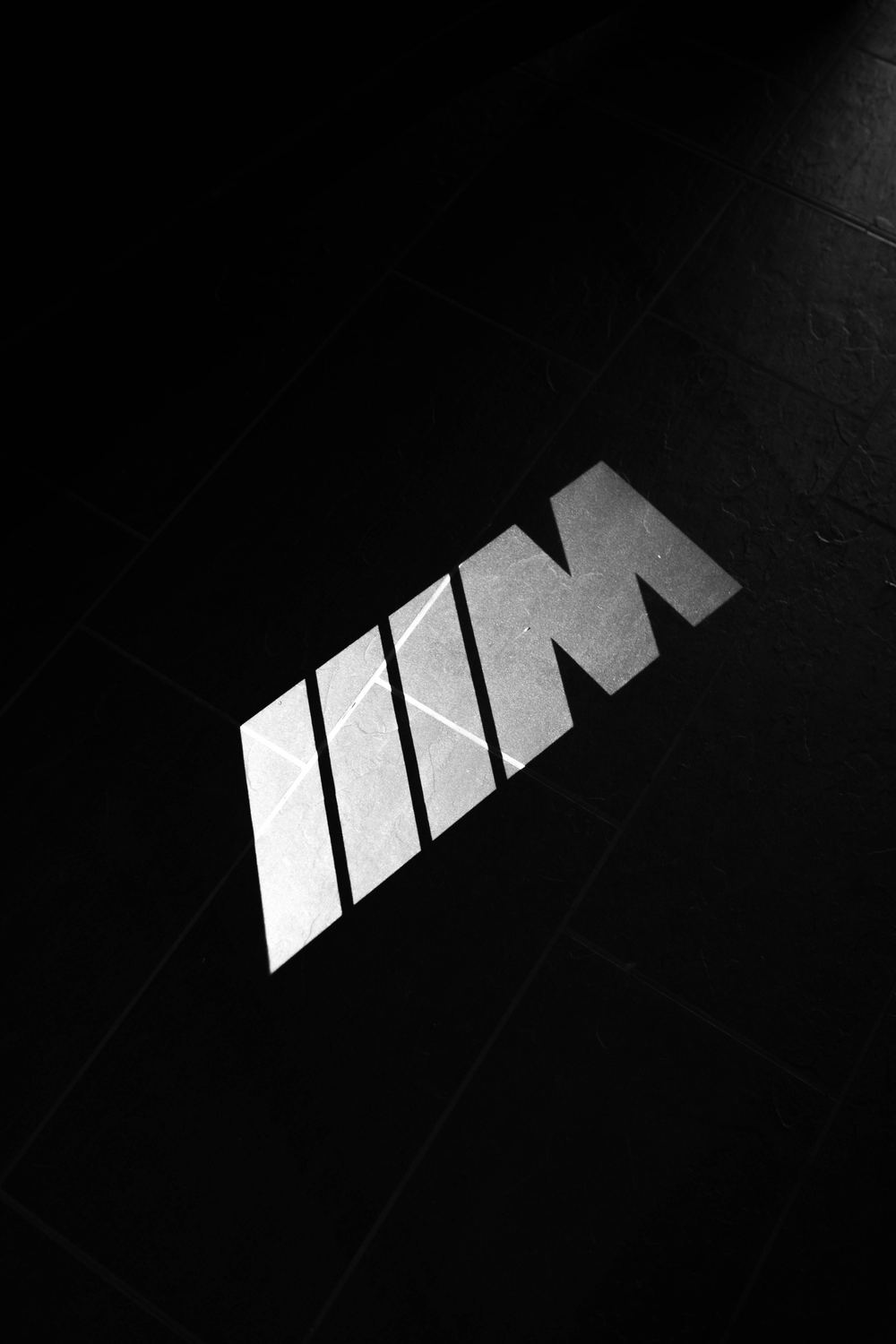 BMW M logo projected onto a dark tiled floor