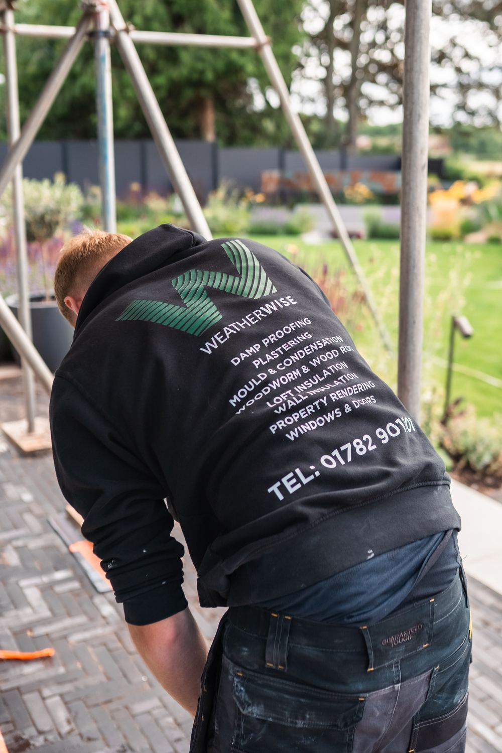 Weatherwise team member on site, company hoodie listing their services