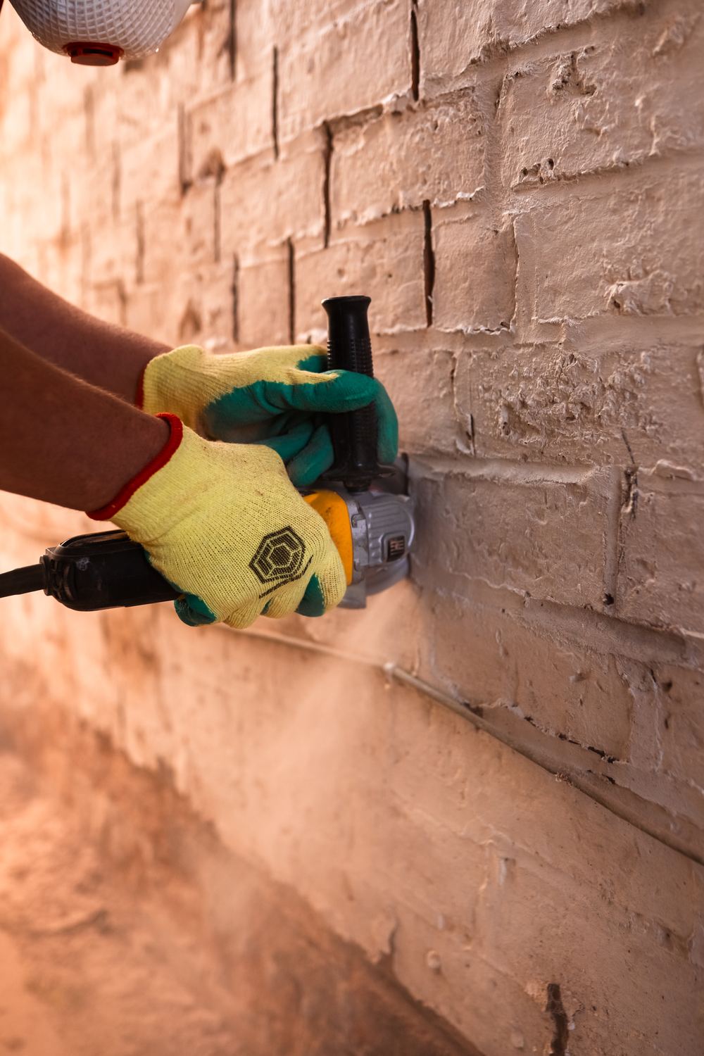 Cutting out mortar joints with a grinder on a painted brick wall