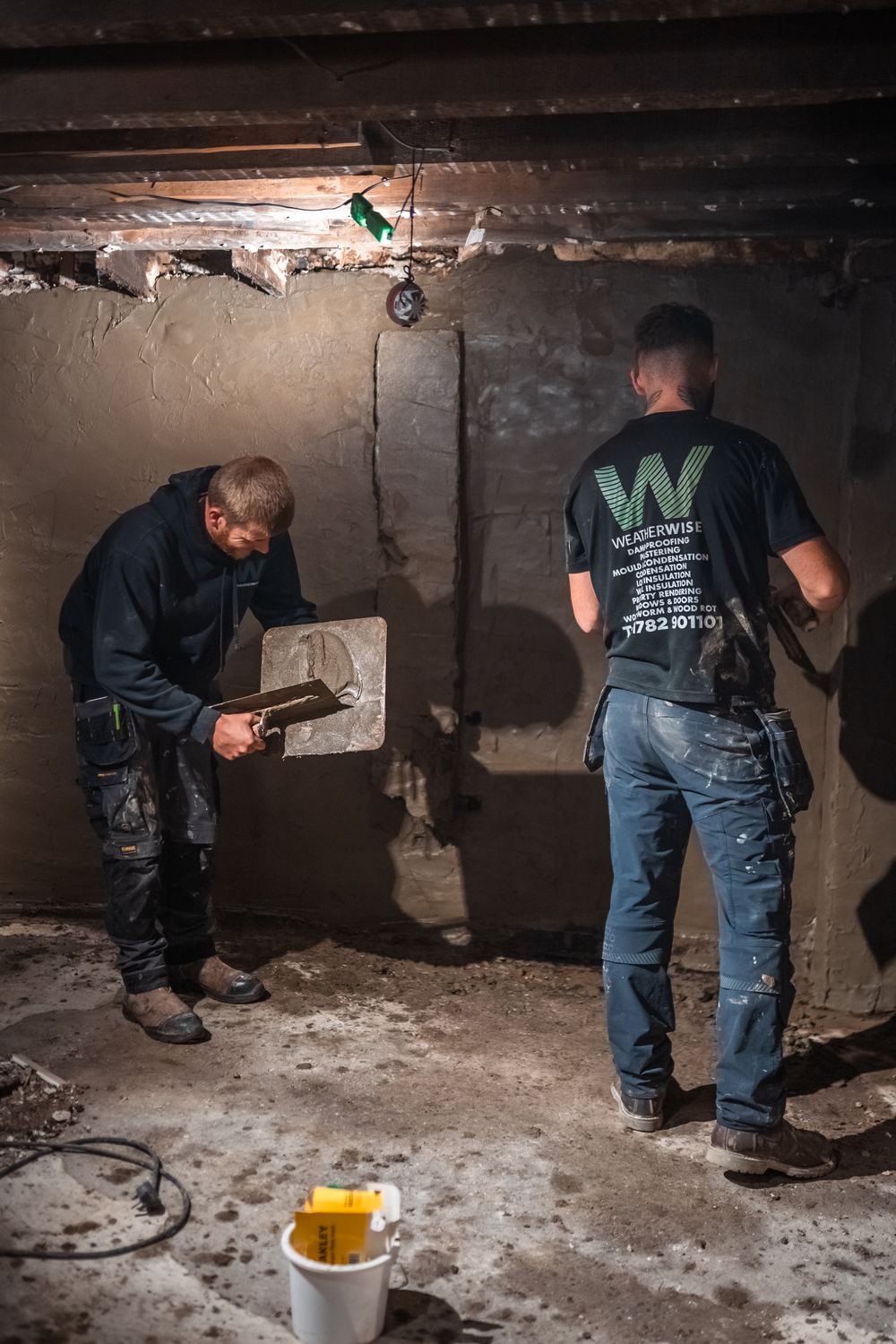 Two Weatherwise plasterers tanking a cellar wall