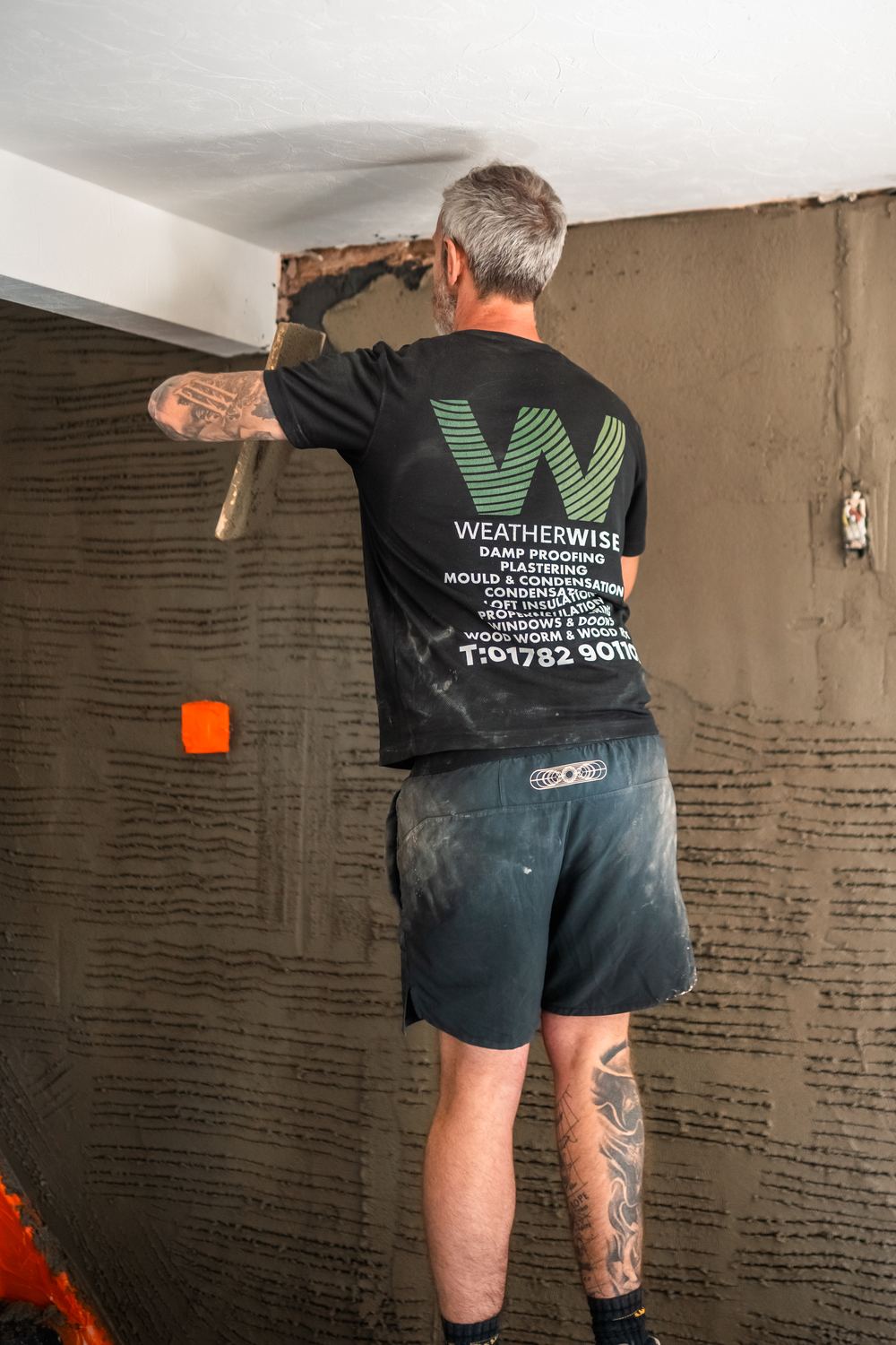 Weatherwise plasterer applying a render coat indoors