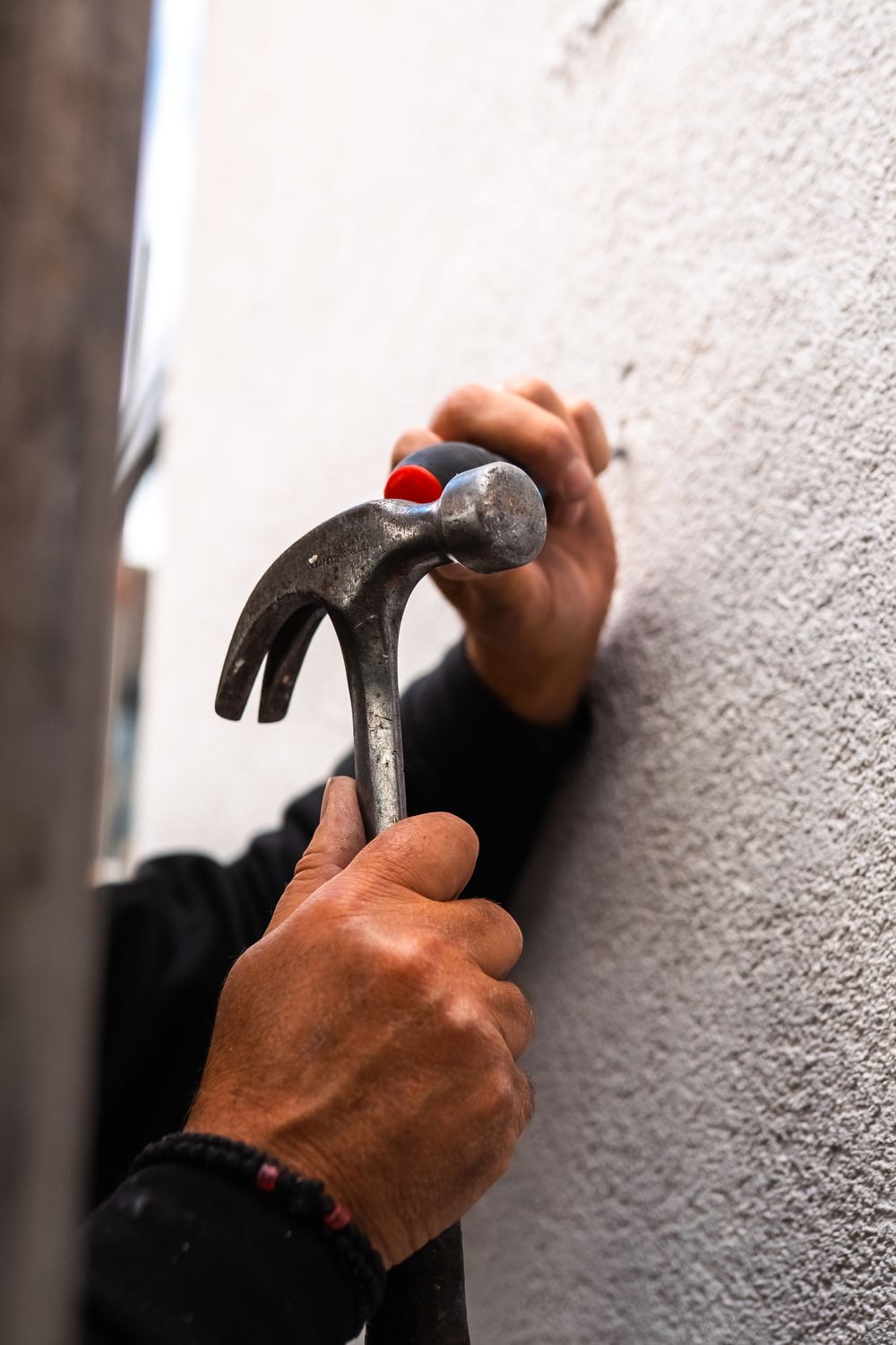 Close-up of a hammer and chisel against a rendered wall